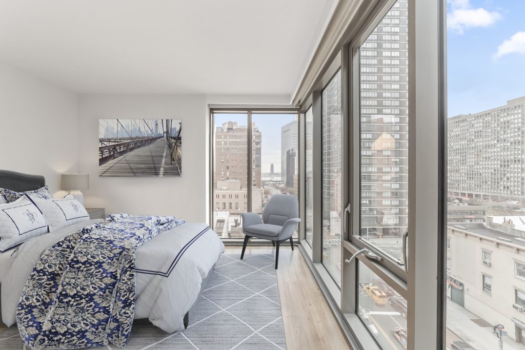 Bedroom with corner windows over Downtown Brooklyn streets and Brooklyn Bridge artwork, by Josh Mak Photography