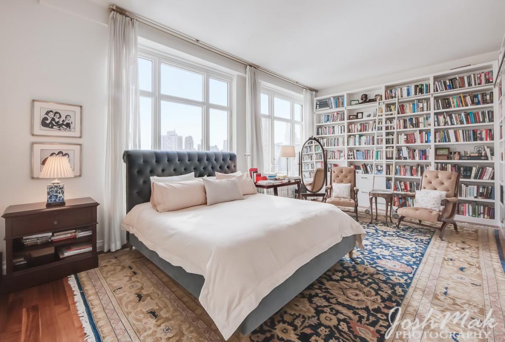 Primary bedroom with floor-to-ceiling library shelving and skyline windows, Upper West Side, by Josh Mak Photography