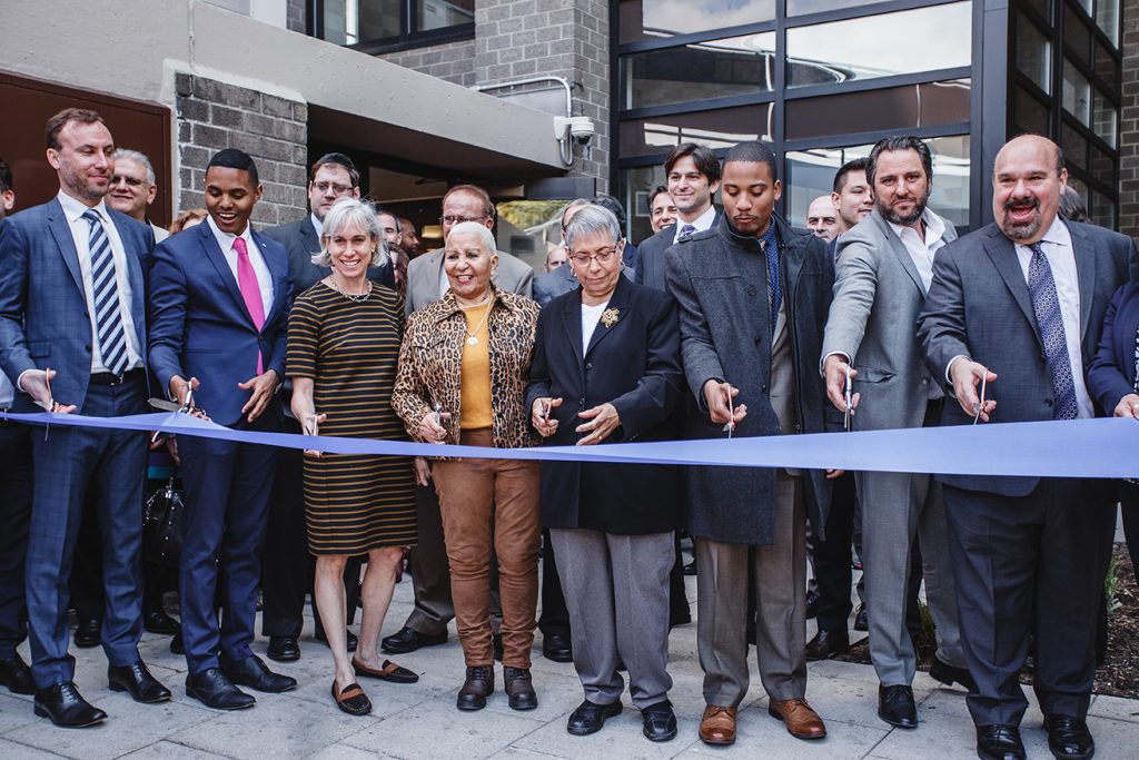 Ribbon-cutting ceremony outside a new building with officials and community members, organization event by Josh Mak Photography